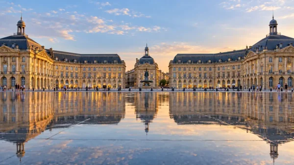 Travel to Bordeaux, France: How to Plan Your First Trip 9 Golden limestone facades of Place de la Bourse reflected in the shallow Miroir d'eau in Bordeaux.