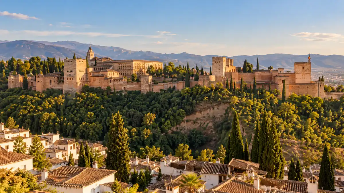 Travel to Granada, Spain: Plan Your Trip Around the Alhambra 2 Warm stone towers of the Alhambra above wooded slopes, seen across the Darro valley in Granada.