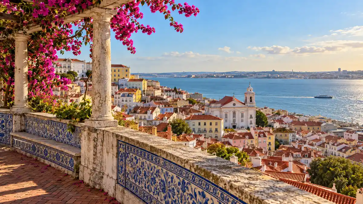 Home 24 Blue-and-white tiled viewpoint with bougainvillea overlooking Alfama rooftops and the Tagus in Lisbon