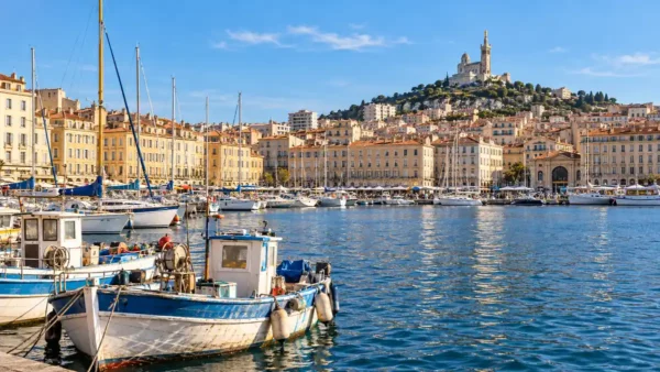 Travel to Marseille, France: How to Plan Your First Trip 9 Moored boats in Marseille's Vieux-Port with Notre-Dame de la Garde rising above the buildings beyond.