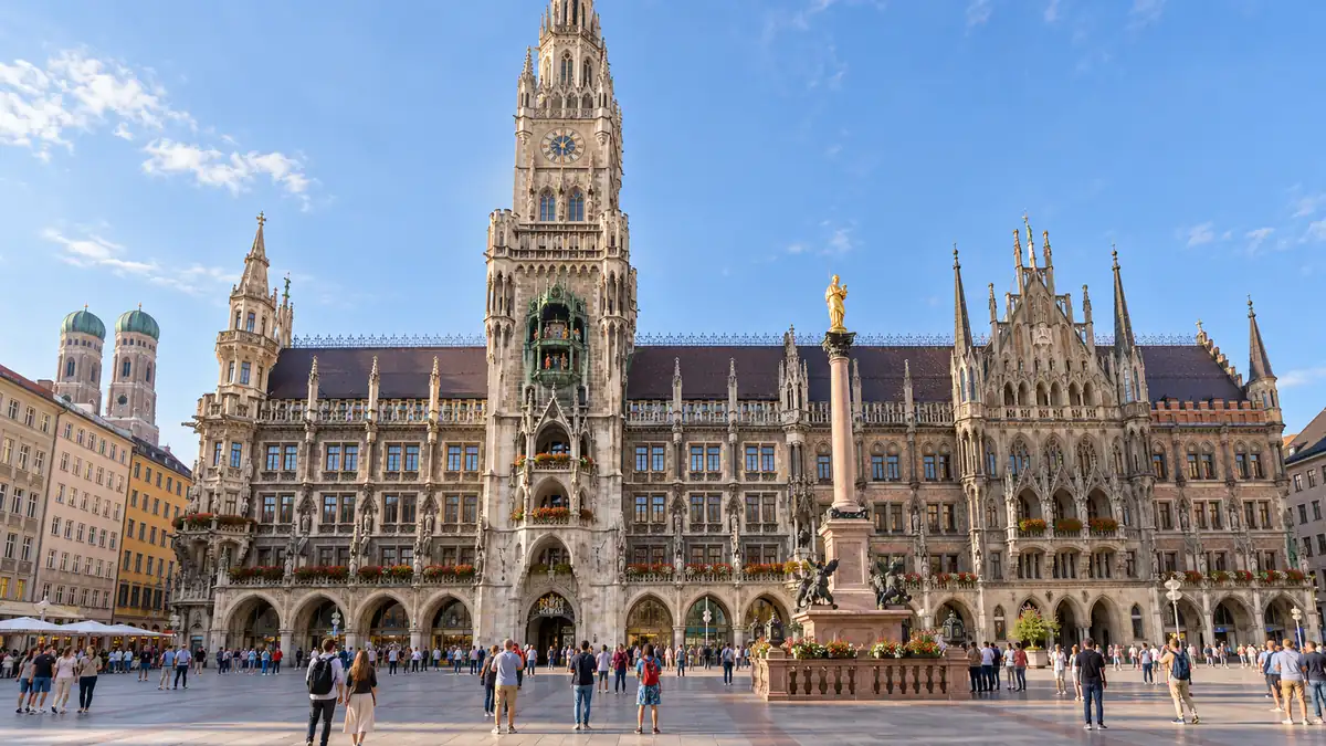 Things to Do in Munich: Which Sights Are Worth Your Time 2 The neo-Gothic New Town Hall overlooks Marienplatz in Munich, with small groups of visitors crossing the square.